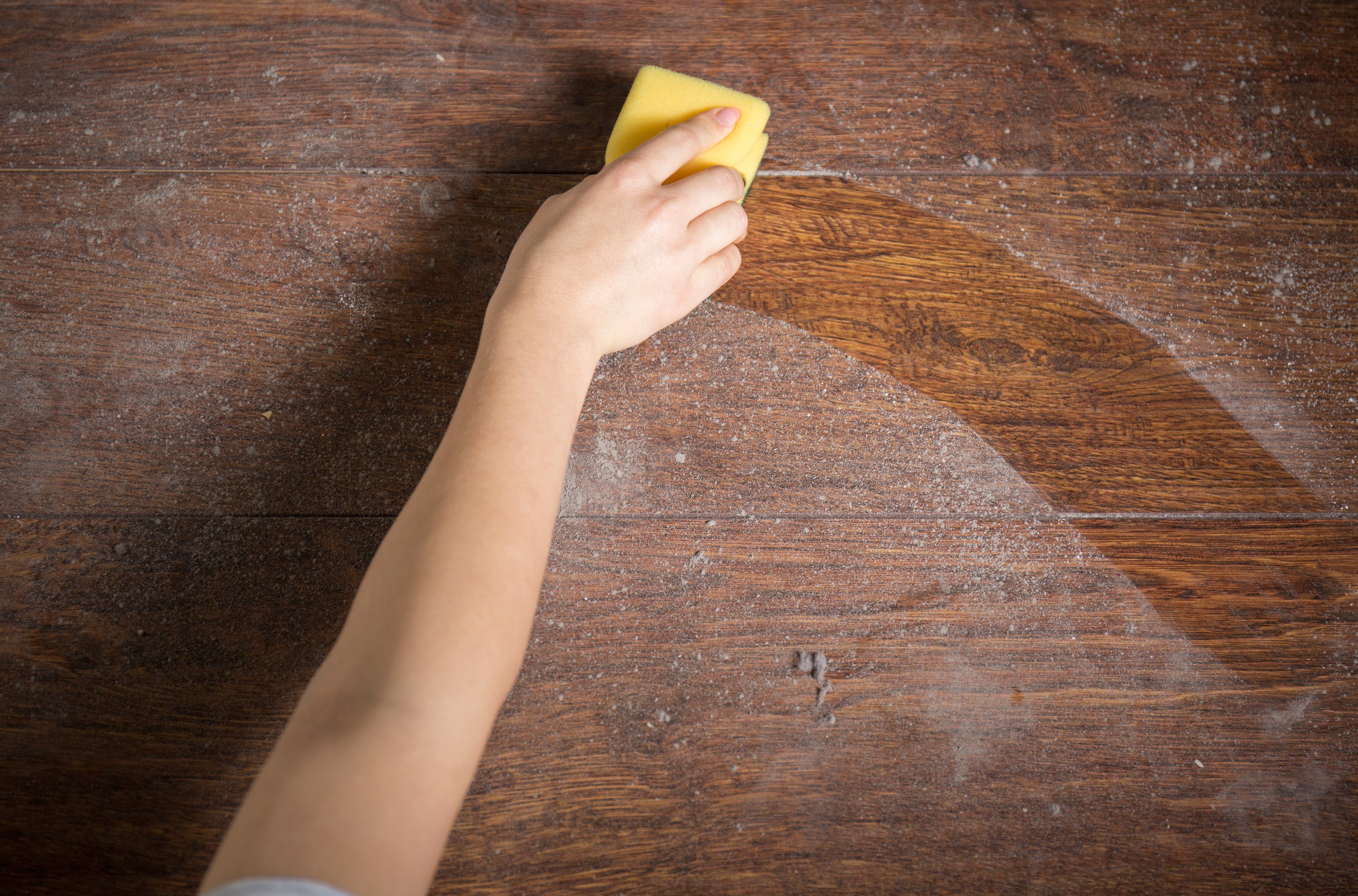 Using yellow sponge for cleaning dusty wood