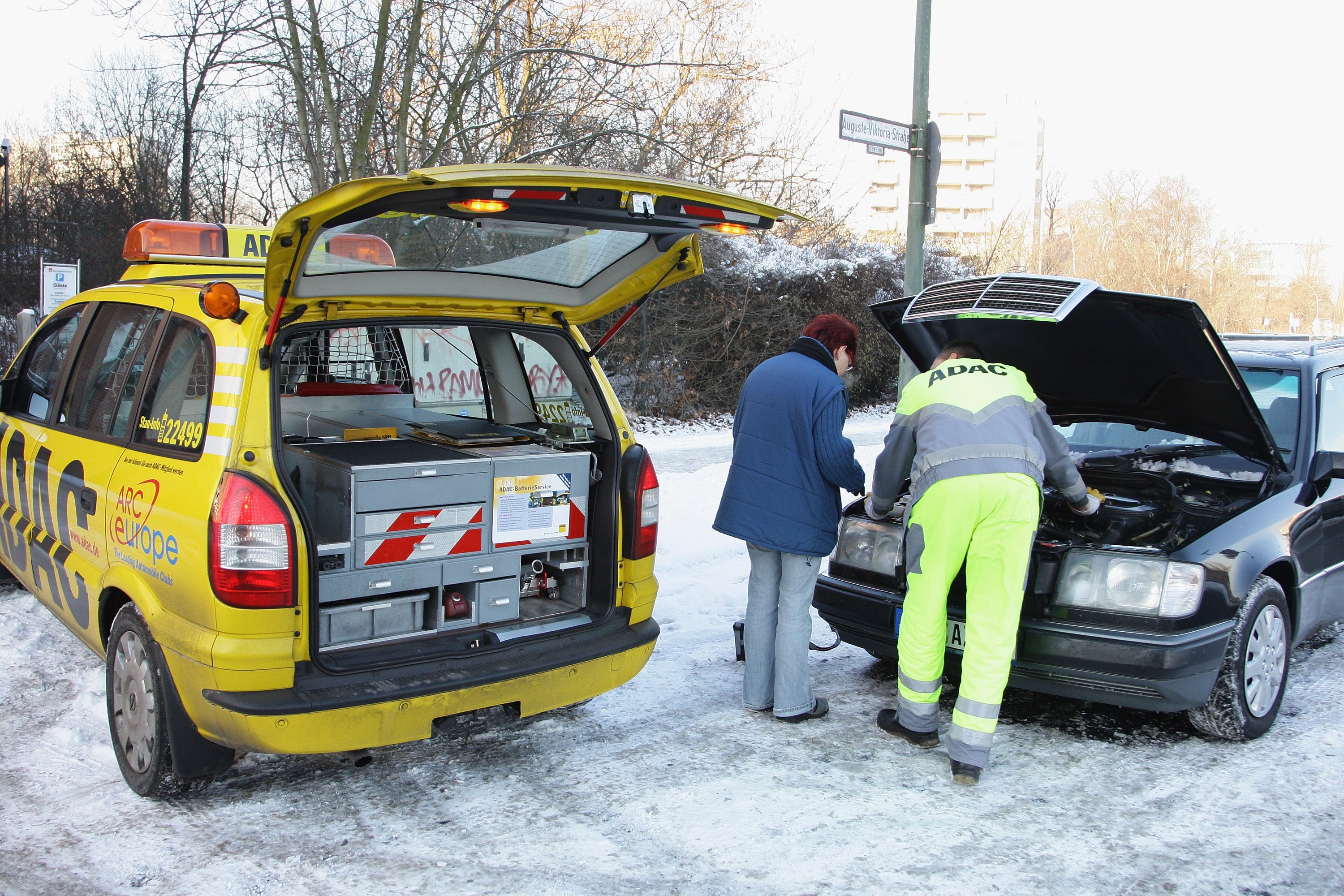 BERLIN - JANUARY 06:  An ADAC (Allgemeiner Deutscher Automobil-Club e.V. - Germany's and Europe's largest automobile club) technical assistant helps a woman with her broken down car on January 6, 2009 in Berlin, Germany. Freezing conditions with snow, ice and temperatures at 20 degrees below zero hits Germany last night.  (Photo by Andreas Rentz/Getty Images)