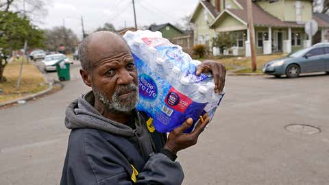 Houstton resident Kenneth Henderson carries a case of donated water back to his home, which still does not have running water, Friday, February 26, 2021. (AP Photo/David J. Phillip)