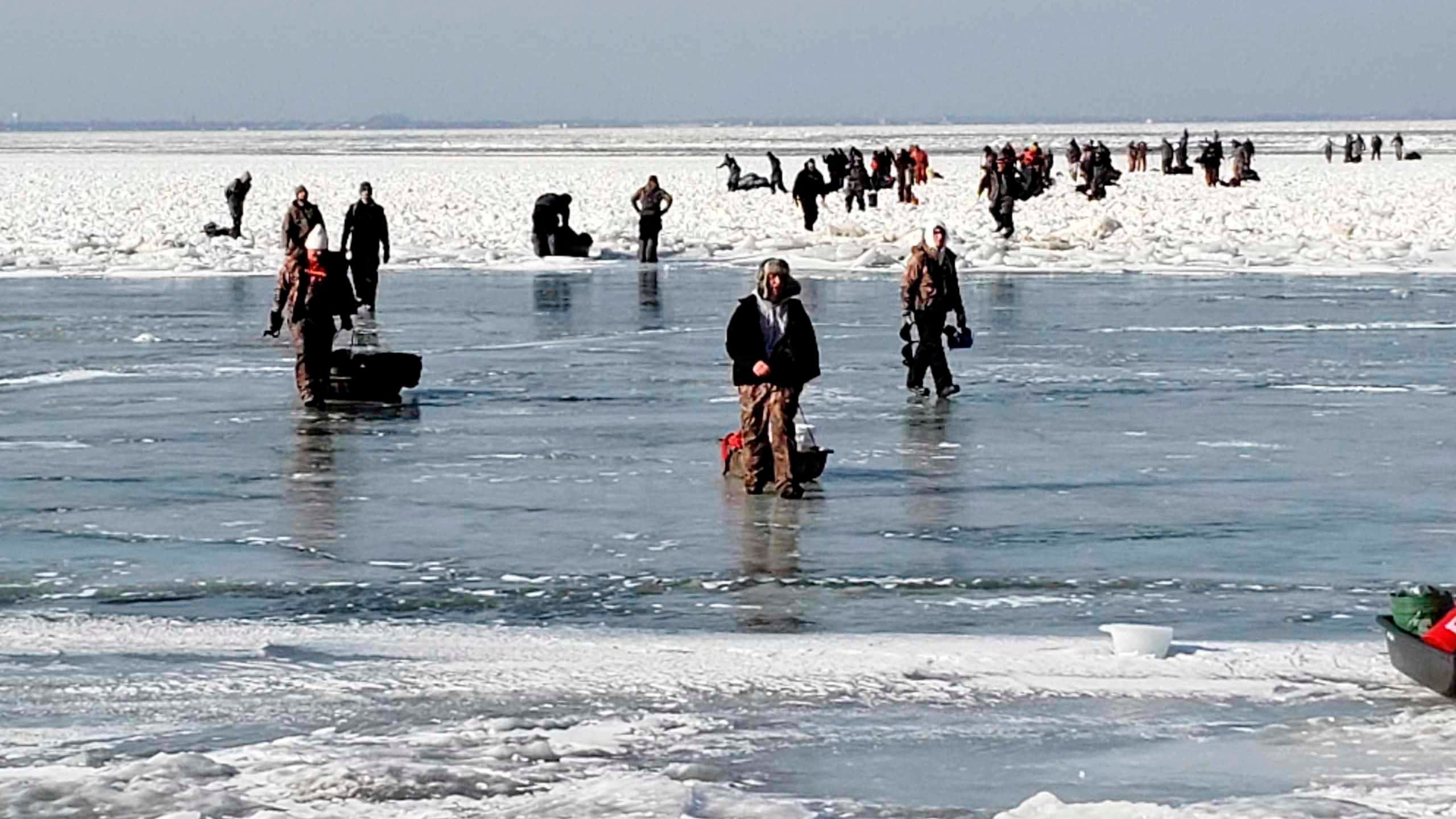In this photo provided by the U.S. Coast Guard, ice fishermen walk to land after being stuck on an ice floe that broke free from land north of Catawba Island, Saturday, March 9, 2019, in Ohio. People were rescued by Coast Guard and local agencies via airboats and others were able to self-rescue by walking across ice-bridges or swimming in the water. (U.S. Coast Guard via AP)