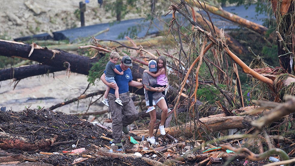 People climb over debris on a bridge atop the Guadalupe River on Saturday after a flash flood swept through the area Friday in Ingram, Texas. (AP Photo/Julio Cortez)

