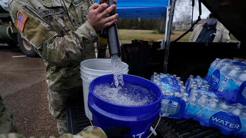 Mississippi Army National Guard Sgt. Chase Toussaint with the Maneuver Area Training Equipment Site of Camp Shelby, right, fills 5-gallon buckets with non-potable water, Monday, March 1, 2021, at a Jackson, Mississippi, water distribution site on the New Mt. Zion Missionary Baptist Church parking lot. Water for flushing toilets was being distributed at seven sites in Mississippi's capital city — more than 10 days after winter storms wreaked havoc on the city's water system because the system is still struggling to maintain consistent water pressure, authorities said. (AP Photo/Rogelio V. Solis)