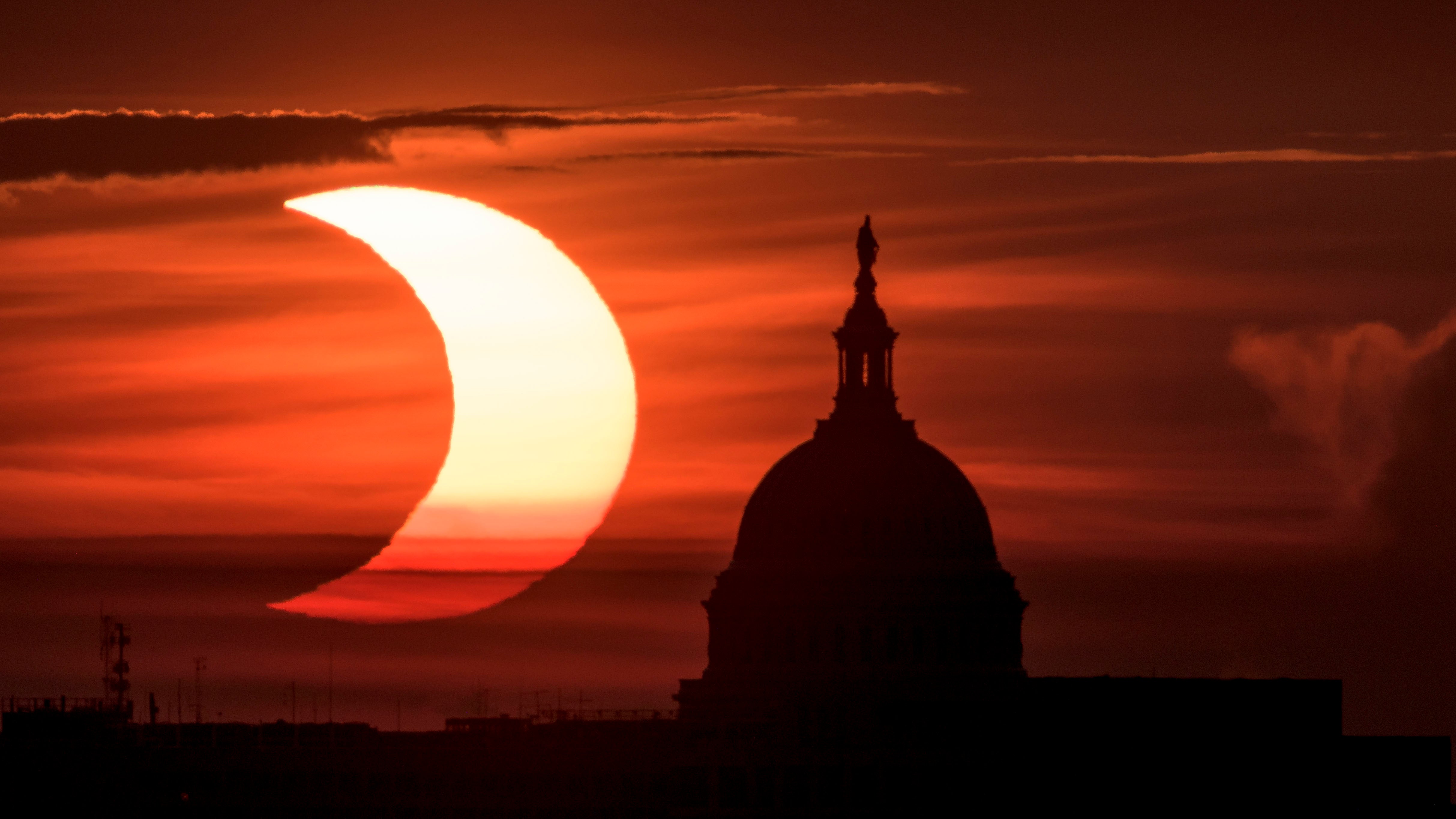 A partial solar eclipse is seen as the sun rises to the left of the United States Capitol building, Thursday, June 10, 2021, as seen from Arlington, Virginia. The annular or &ldquo;ring of fire&rdquo; solar eclipse is only visible to some people in Greenland, Northern Russia, and Canada. Photo Credit: (NASA/Bill Ingalls)