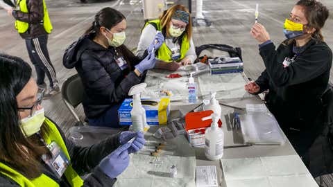 Medical professionals from Oregon Health & Science University load syringes with the Moderna COVID-19 vaccine at a drive-thru vaccination clinic in Portland, Oregon on Sunday, January 10, 2021. The U.S. is entering the second month of the largest vaccination effort in history with a massive expansion of the campaign, opening up football stadiums, major league ballparks, fairgrounds and convention centers to inoculate a larger and more diverse pool of people. (Kristyna Wentz-Graff/Pool Photo via AP)
