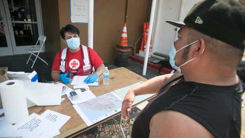 August 22, 2020. Santa Rosa, California.Red Cross shelter at the Sonoma County Fairgrounds in Santa Rosa, California. Omar Padilla is asked Covid-19 health screening questions by Red Cross volunteer Cristian Calvillo before entering the shelter.Photo by Dennis Drenner/American Red Cross