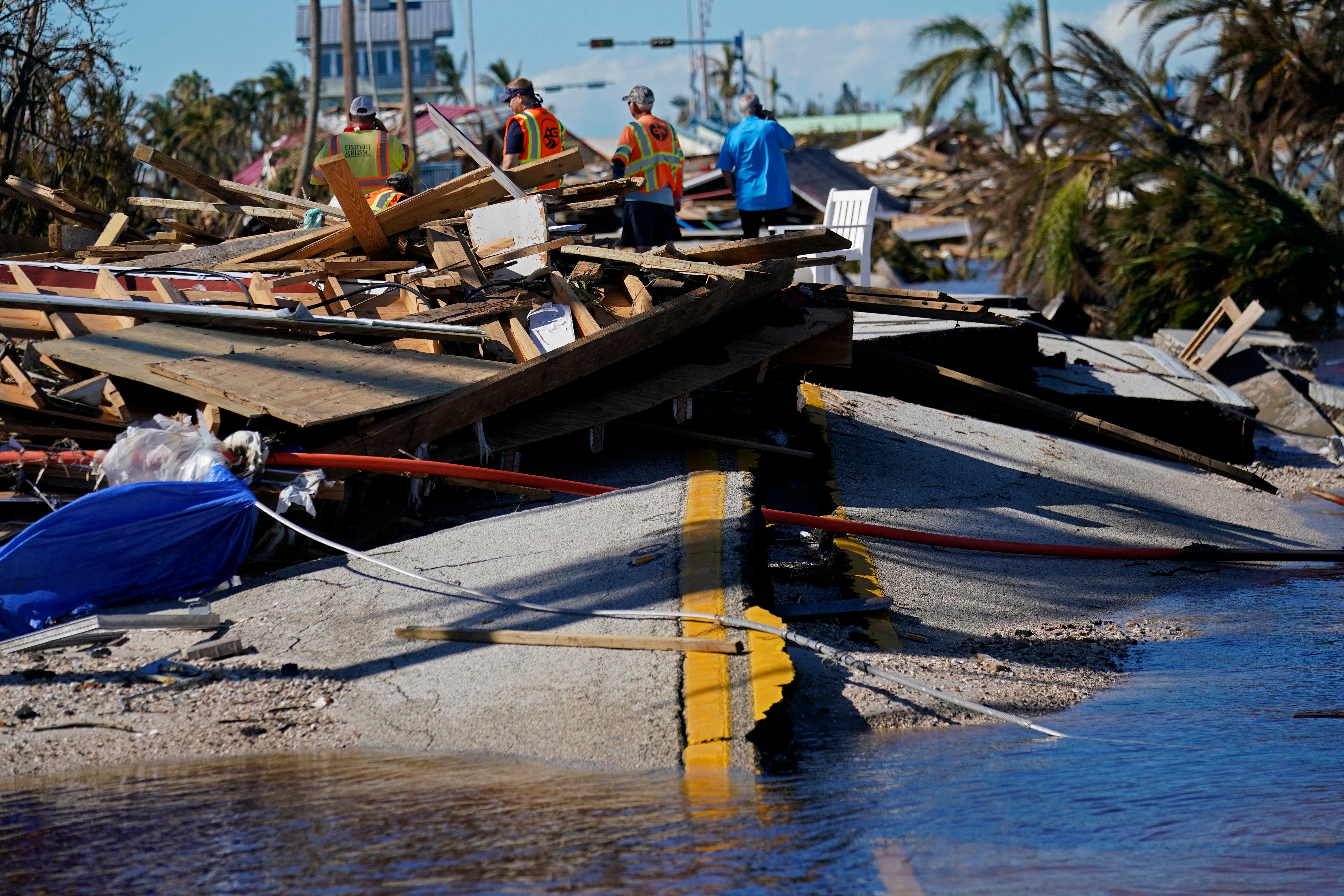 Responders from the de Moya Group survey damage to the bridge leading to Pine Island, to start building temporary access to the island in the aftermath of Hurricane Ian in Matlacha, Fla., Sunday, Oct. 2, 2022. The only bridge to the island is heavily damaged so it can only be reached by boat or air. (AP Photo/Gerald Herbert)