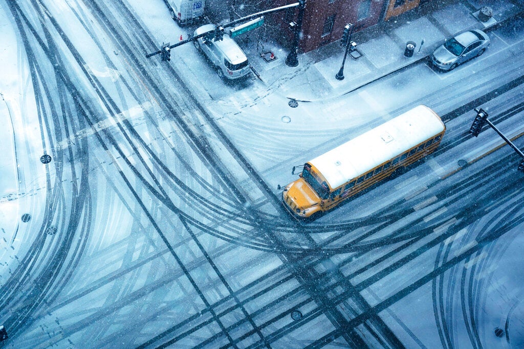 A school bus crosses a snow-covered intersection, Thursday, Feb. 16, 2023, in Waukegan, Ill. (AP Photo/Nam Y. Huh)
