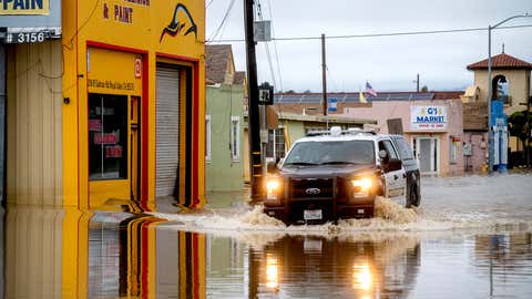 A sheriff's deputy drives through floodwaters in the community of Pajaro in Monterey County, Calif., on Monday, March 13, 2023. (AP Photo/Noah Berger)