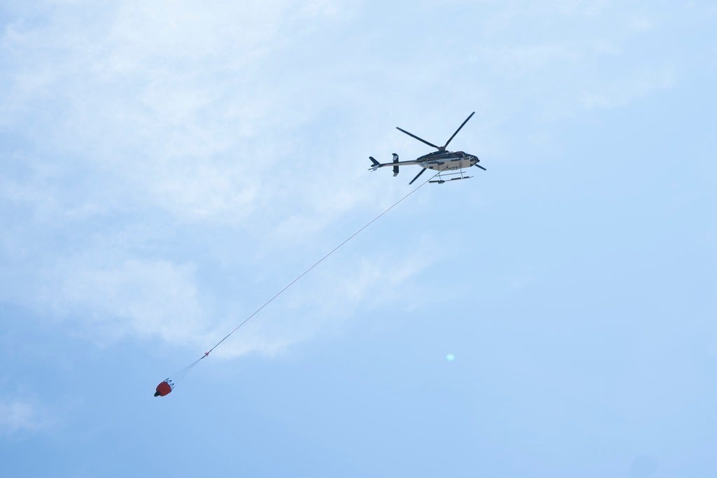 A waterbombing helicopter is seen carrying water as emergency responders battle the wildfire burning in Tantallon, Nova Scotia, outside of Halifax on Wednesday, May 31, 2023. (Darren Calabrese/The Canadian Press via AP)