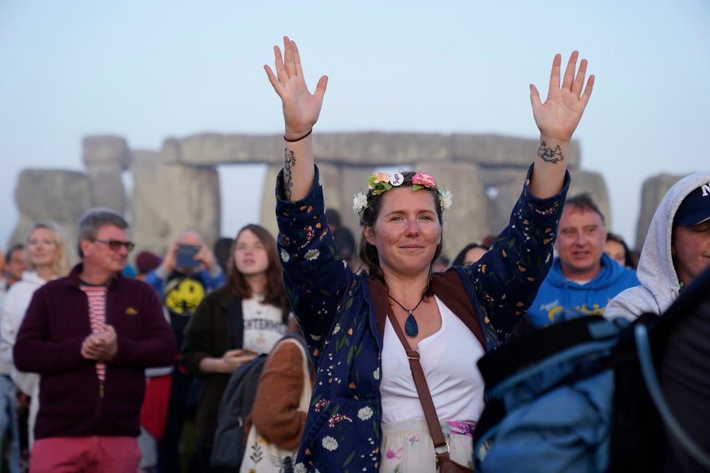 People gather during sunrise as they take part in the summer solstice at Stonehenge in Wiltshire, England Wednesday, June 21, 2023. (Andrew Matthews/PA via AP)