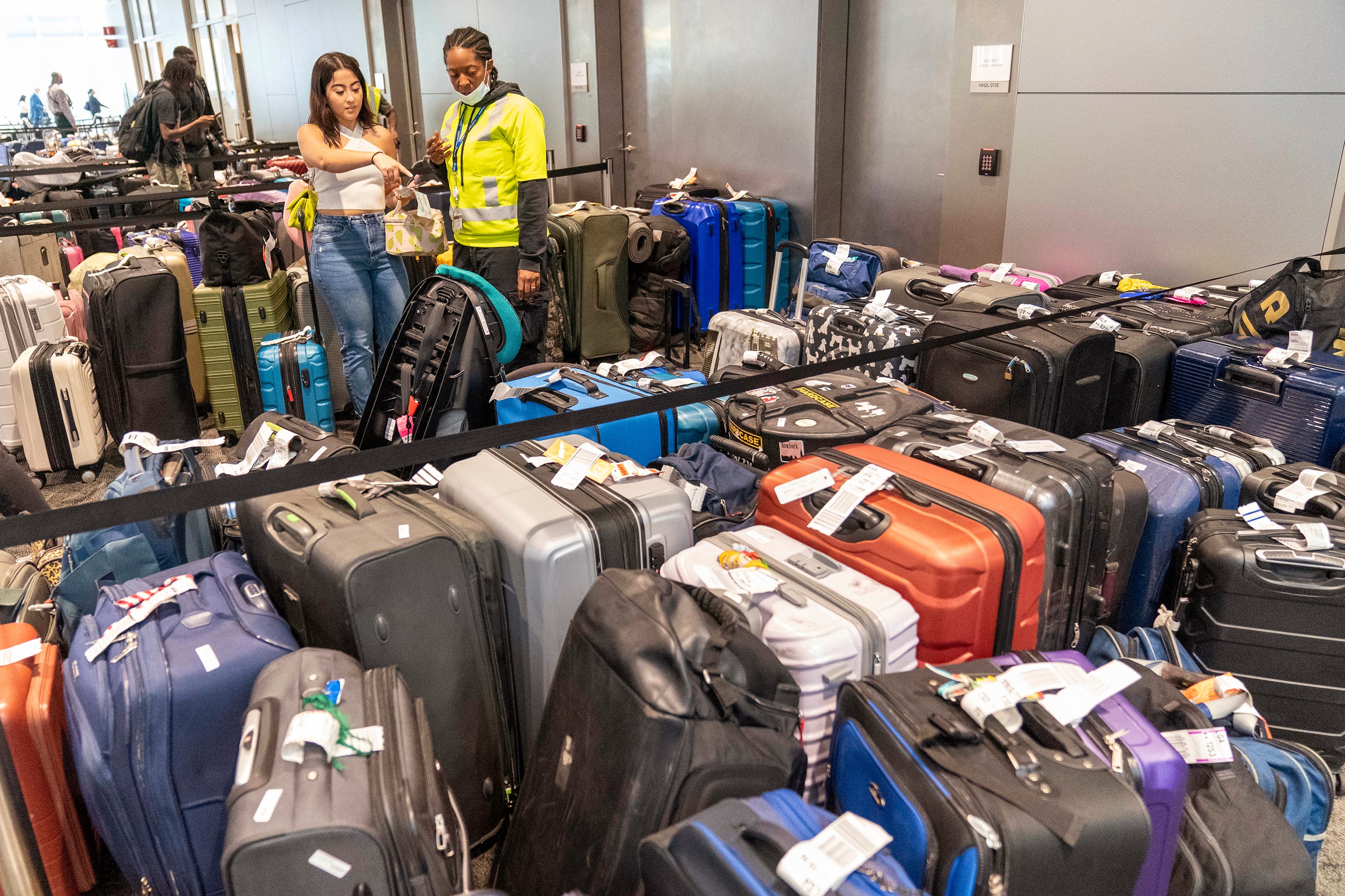 An airline employee, right, helps a traveler find her suitcase amongst the unclaimed luggage in the arrivals area of Terminal B at LaGuardia Airport, Tuesday, June 27, 2023, in New York.  Travelers waited out widespread delays at U.S. airports on Tuesday, an ominous sign heading into the long July 4 holiday weekend, which is shaping up as the biggest test yet for airlines that are struggling to keep up with surging numbers of passengers. (AP Photo/Mary Altaffer)