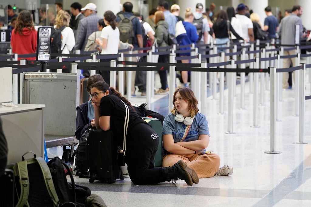 Travelers sit on the ground at the departure area at the United Airlines terminal at Los Angeles International Airport, Wednesday June 28, 2023, in Los Angeles. Travelers waited out widespread delays at U.S. airports on Tuesday, an ominous sign heading into the long July 4 holiday weekend, which is shaping up as the biggest test yet for airlines that are struggling to keep up with surging numbers of passengers. (AP Photo/Damian Dovarganes)