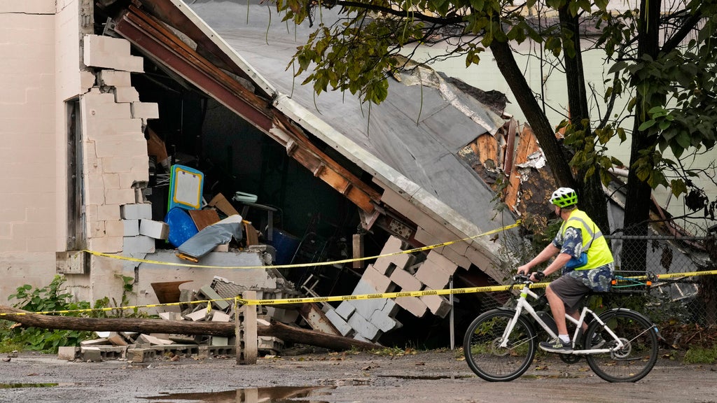 A man views damage to a building caused by recent flooding, Wednesday, Sept. 13, 2023, at the Hilton & Cook Marketplace in Leominster, Mass. (AP Photo/Robert F. Bukaty)