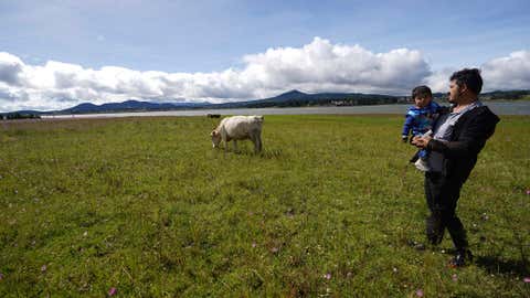 Gabriel Bejarano and his son Leo stand on his grandfather's farm on the banks of the Villa Victoria reservoir in the State of Mexico, Tuesday, Oct. 10, 2023. “I don’t know the exact level, but it’s the lowest in recent years,” said the veterinarian, at least since he moved back onto his grandfather’s farm in 2013. (AP Photo/Marco Ugarte)