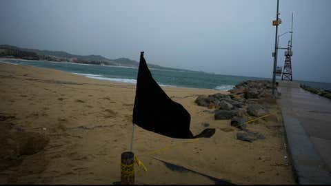 A black flag waves in the wind, signaling a closed beach, prior the arrival of the hurricane Norma in Cabo San Lucas, Mexico, Friday, Oct. 20, 2023. Hurricane Norma is heading for the resorts of Los Cabos at the southern tip of Mexico's Baja California Peninsula, while Tammy grew into a hurricane in the Atlantic. (AP Photo/Fernando Llano)
