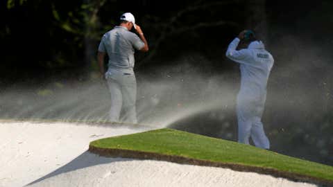 Rory McIlroy, of Northern Ireland, and his caddy Harry Diamond shield themselves from the blondes on on the 11th hole during the second round at the Masters golf tournament at Augusta National Golf Club Friday, April 12, 2024, in Augusta, Georgia. (AP Photo/Charlie Riedel)