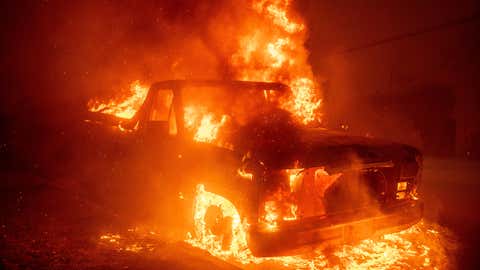 The Eaton Fire burns a vehicle Wednesday, Jan. 8, 2025 in Altadena, Calif. (AP Photo/Ethan Swope)
