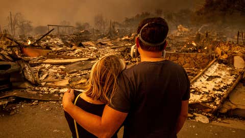 Megan Mantia, left, and her boyfriend Thomas, return to Mantia's fire-damaged home after the Eaton Fire swept through, Wednesday, Jan. 8, 2025, in Altadena, Calif. (AP Photo/Ethan Swope)
