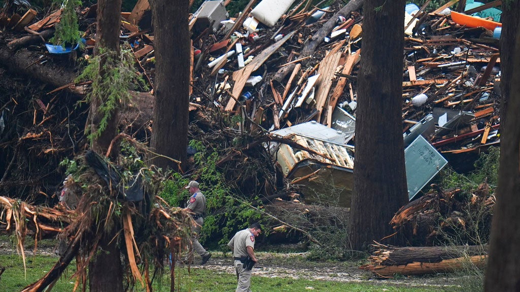 Officials comb through the banks of the Guadalupe River after a flash flood swept through the area Saturday, July 5, 2025, in Hunt, Texas. (AP Photo/Julio Cortez)