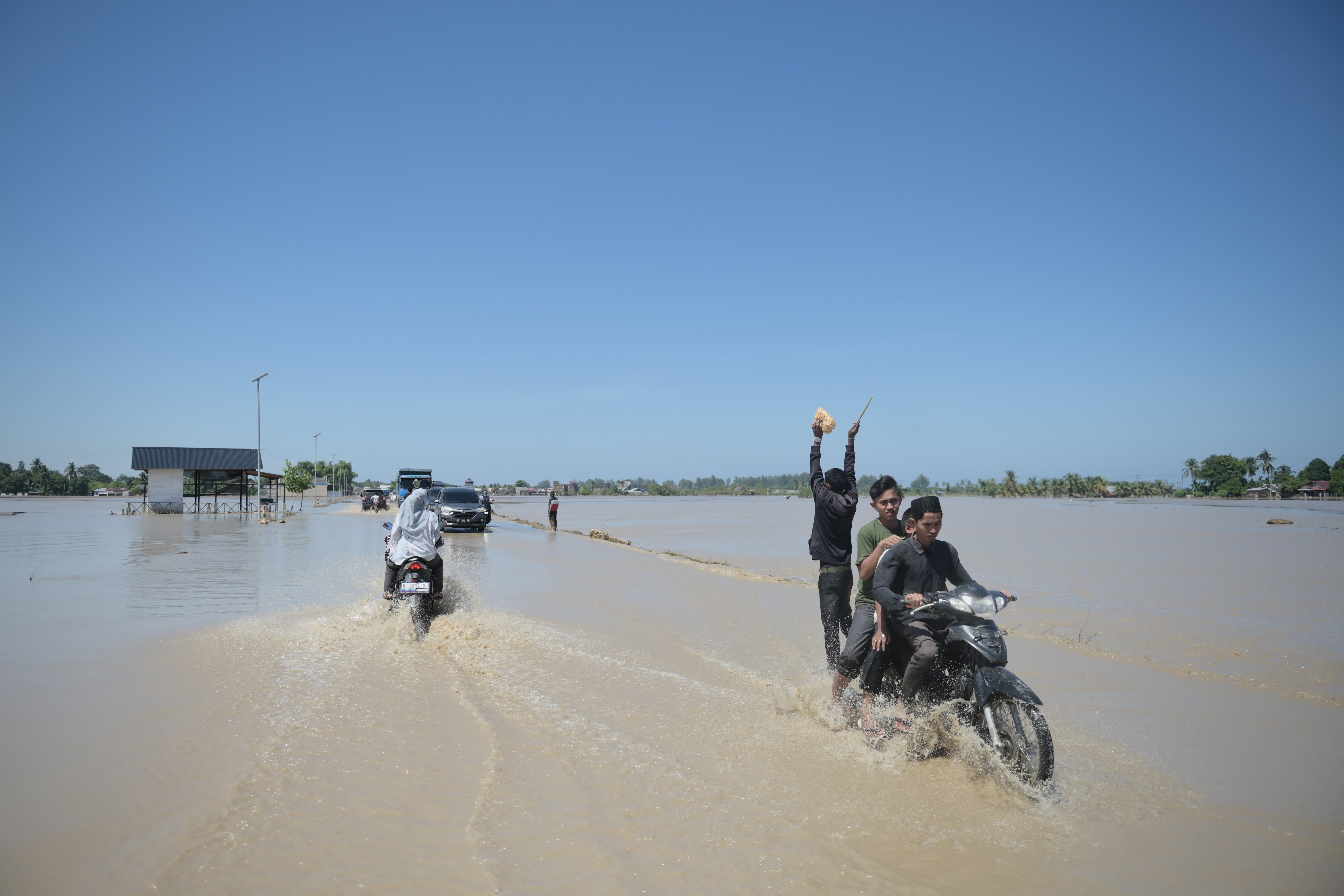 Motorists ride on a flooded street in Pidie Jaya, Aceh province, Indonesia, Saturday, Nov.29, 2025. (AP Photo/Reza Saifullah)