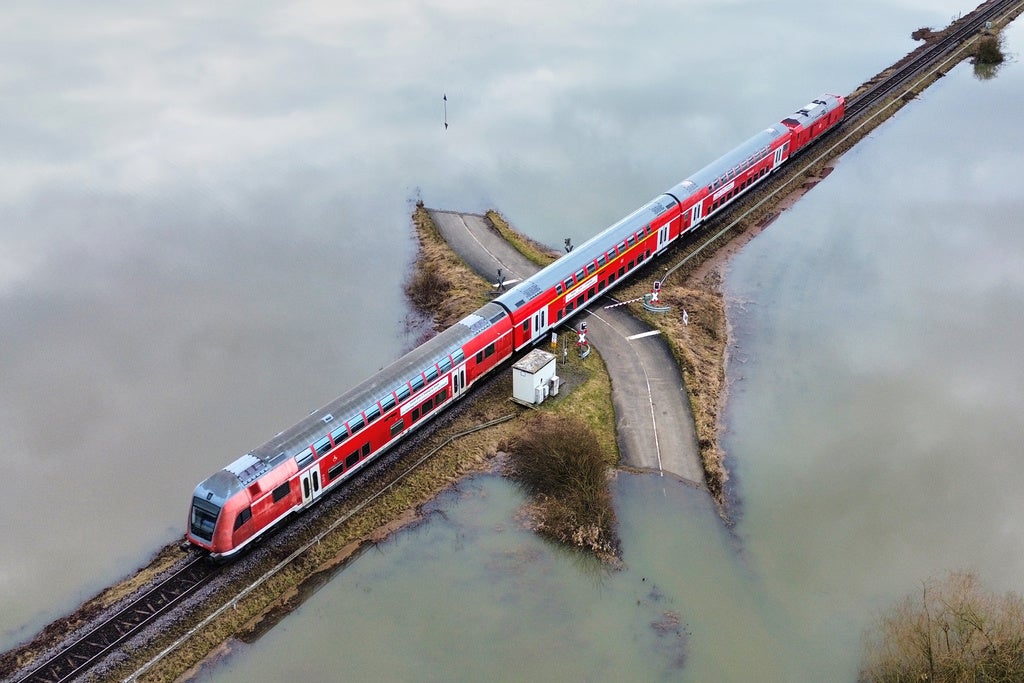 A regional train passes a railroad crossing between flooded fields in Nidderau-Eichen near Frankfurt, Germany, Wednesday, Feb. 18, 2026. (AP Photo/Michael Probst)
