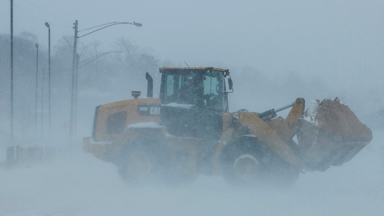 A loader moves sand from a parking lot back to Pere Marquette Beach in Muskegon, Mich. on Wednesday, April 4, 2018.  A spring storm dumped more than a foot of snow in parts of Michigan's northern Lower Peninsula and is blamed for creating hazardous road conditions.  (Joel Bissell /Muskegon Chronicle via AP)