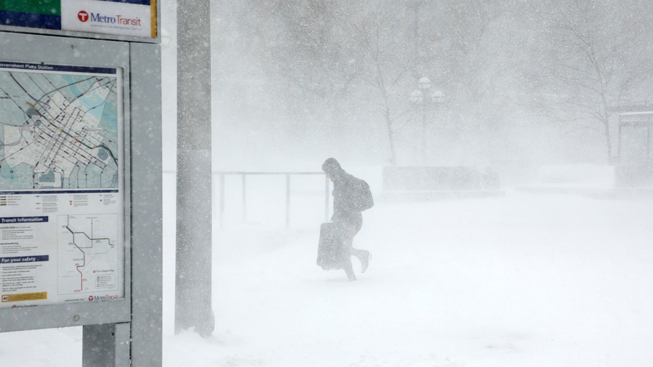A traveler walks through the snow and ice to get to the Metro Government Center Plaza station as the snow picked up in downtown Minneapolis, Saturday, April 14, 2018.   The National Weather Service predicts 9 to 15 inches of snow across a large swath of southern Minnesota including the Twin Cities before it's all over. (Anthony Souffle/Star Tribune via AP)