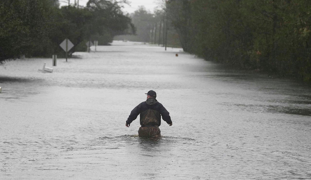 A member of the U.S. Coast Guard walks down Mill Creek Road checking houses after tropical storm Florence hit Newport North Carolina, on Saturday, September 15, 2018. A day after blowing ashore with 90 mph winds, Florence practically parked itself over land all day long and poured on the rain. (AP Photo/Tom Copeland)