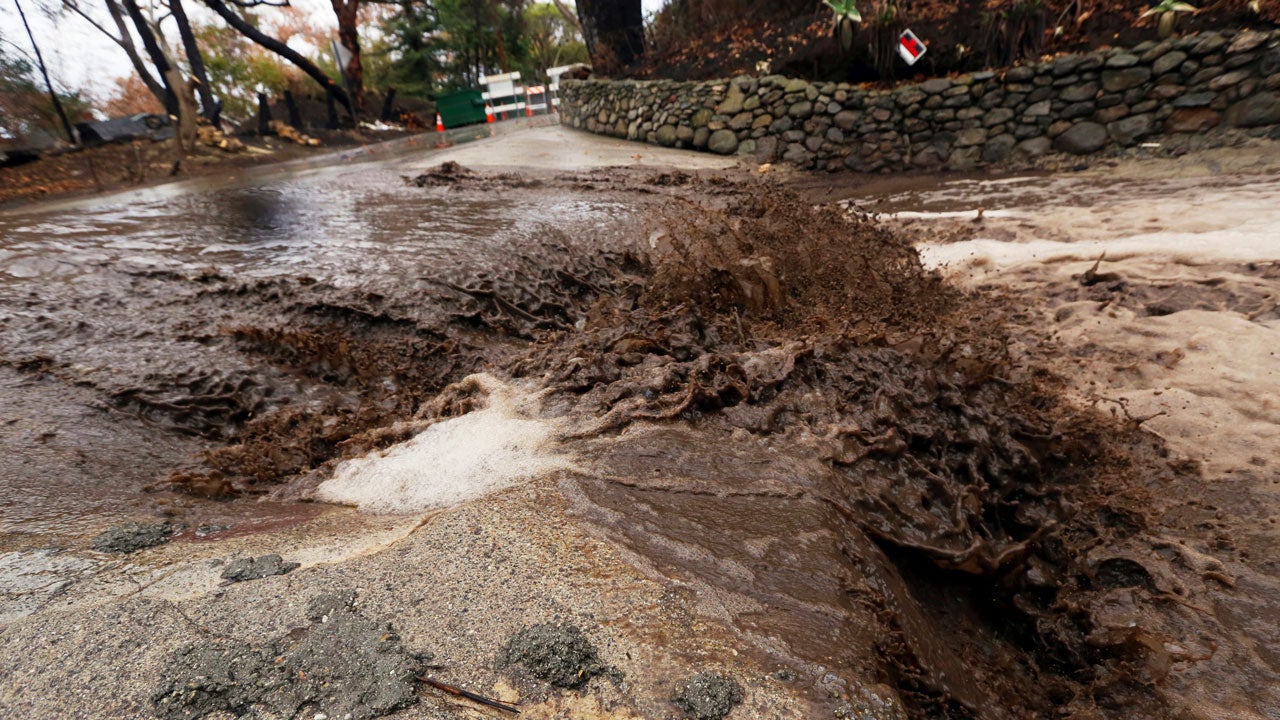 Water loaded with mud and debris churns across a wash on Rainsford Place in Zuma Canyon in an area burned by the Woolsey Fire in Malibu, California, Thursday, Dec. 6, 2018. (AP Photo/Reed Saxon)