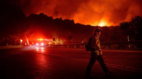 A firefighter crosses Highway 154 while battling the Cave Fire in Los Padres National Forest, Calif., above Santa Barbara on Tuesday, Nov. 26, 2019. (AP Photo/Noah Berger)