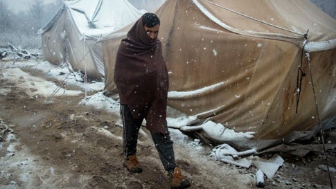 A migrant walks amid tents during snowfall at the Vucjak refugee camp outside Bihac, northwestern Bosnia, Monday, Dec. 2, 2019. Despite calls for their relocation before winter, hundreds of migrants remain stuck in a make-shift tent camp in northwestern Bosnia as a spate of snowy and cold weather hit the region. (AP Photo/Darko Bandic)