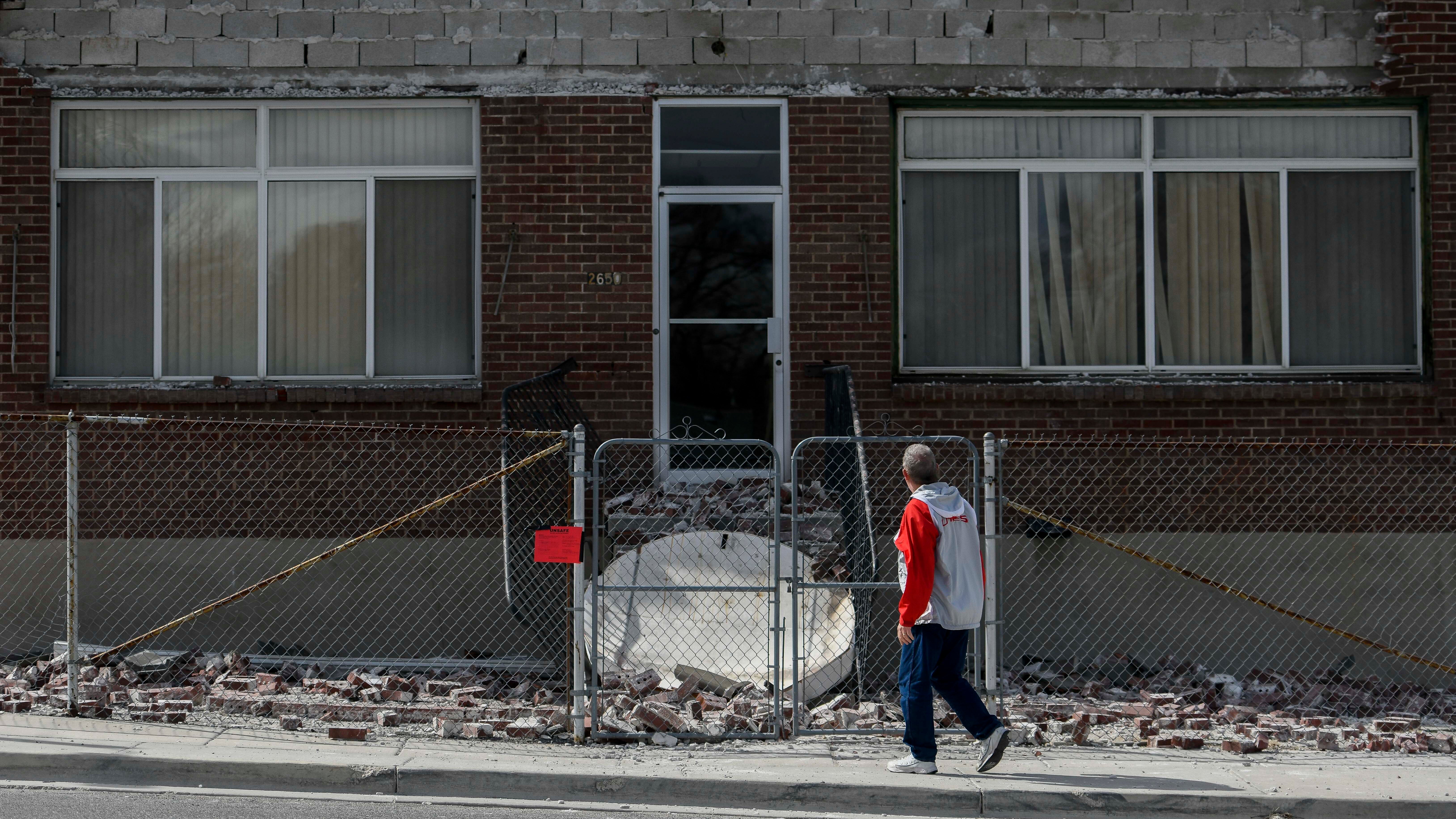 A pedestrian looks at the damage caused by a 5.7 magnitude earthquake Wednesday, March 18, 2020, in Magna, Utah. A moderate earthquake Wednesday near Salt Lake City shut down a major air traffic hub, damaged a spire atop a temple and frightened millions of people already on edge from the coronavirus pandemic. There were no reports of injuries. (AP Photo/Alex Goodlett)