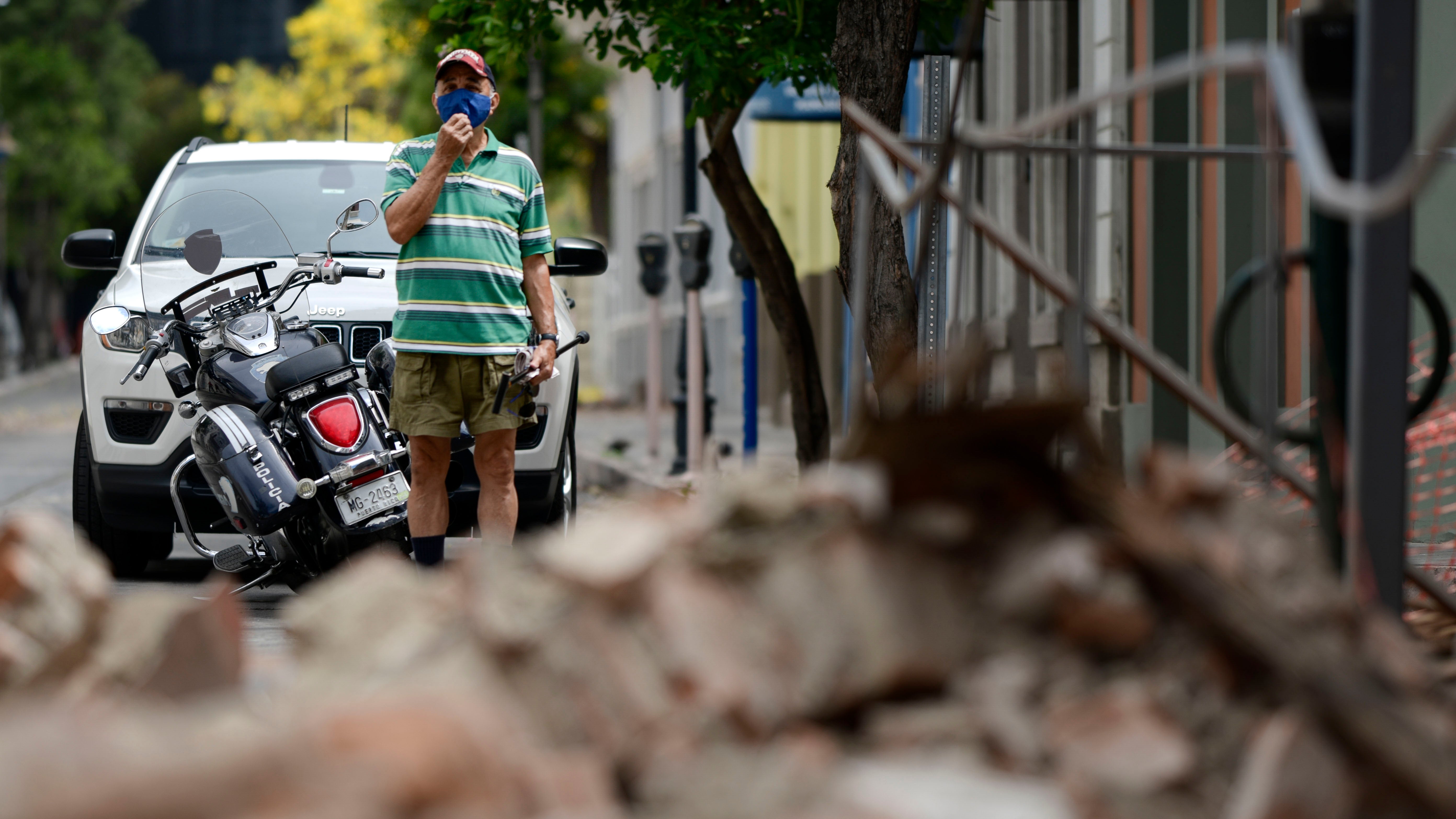 A resident wears a protective face mask as a precaution against the spread of the new coronavirus as he looks at damage caused by a 5.4-magnitude earthquake, in Ponce, Puerto Rico, Saturday, May 2, 2020. The quake hit near southern Puerto Rico, jolting many from their beds on an island where some people still remain in shelters from previous quakes earlier this year. (AP Photo/Carlos Giusti)