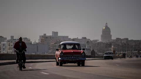 An American classic car and bicycle share the road on the Malecon amid a cloud of Sahara dust in Havana, Cuba, Thursday, June 25, 2020. The dust cloud is blanketing the Caribbean as it heads to the U.S. with a size and concentration level that meteorologists say hasn't been seen in roughly half a century. (AP Photo / Ramon Espinosa)