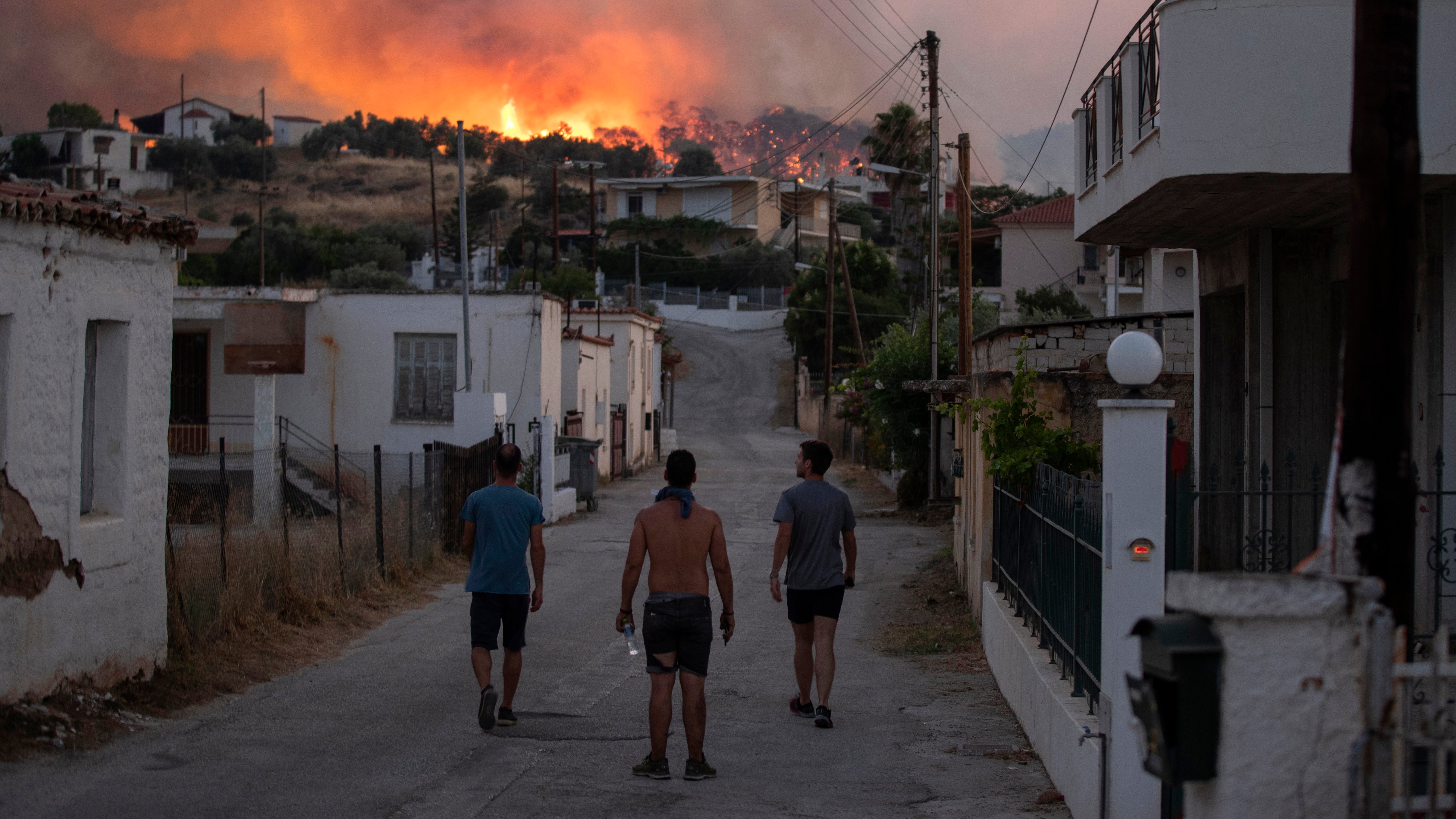 Three men watching the fire that burns near the village of Galataki, near Corinth, Greece, on Wednesday, July 22, 2020. More than 250 firefighters, backed by water-dropping aircraft, were struggling Wednesday to contain a large wildfire fanned by strong winds that has forced the evacuation of five settlements in southern Greece. (AP Photo/Petros Giannakouris)