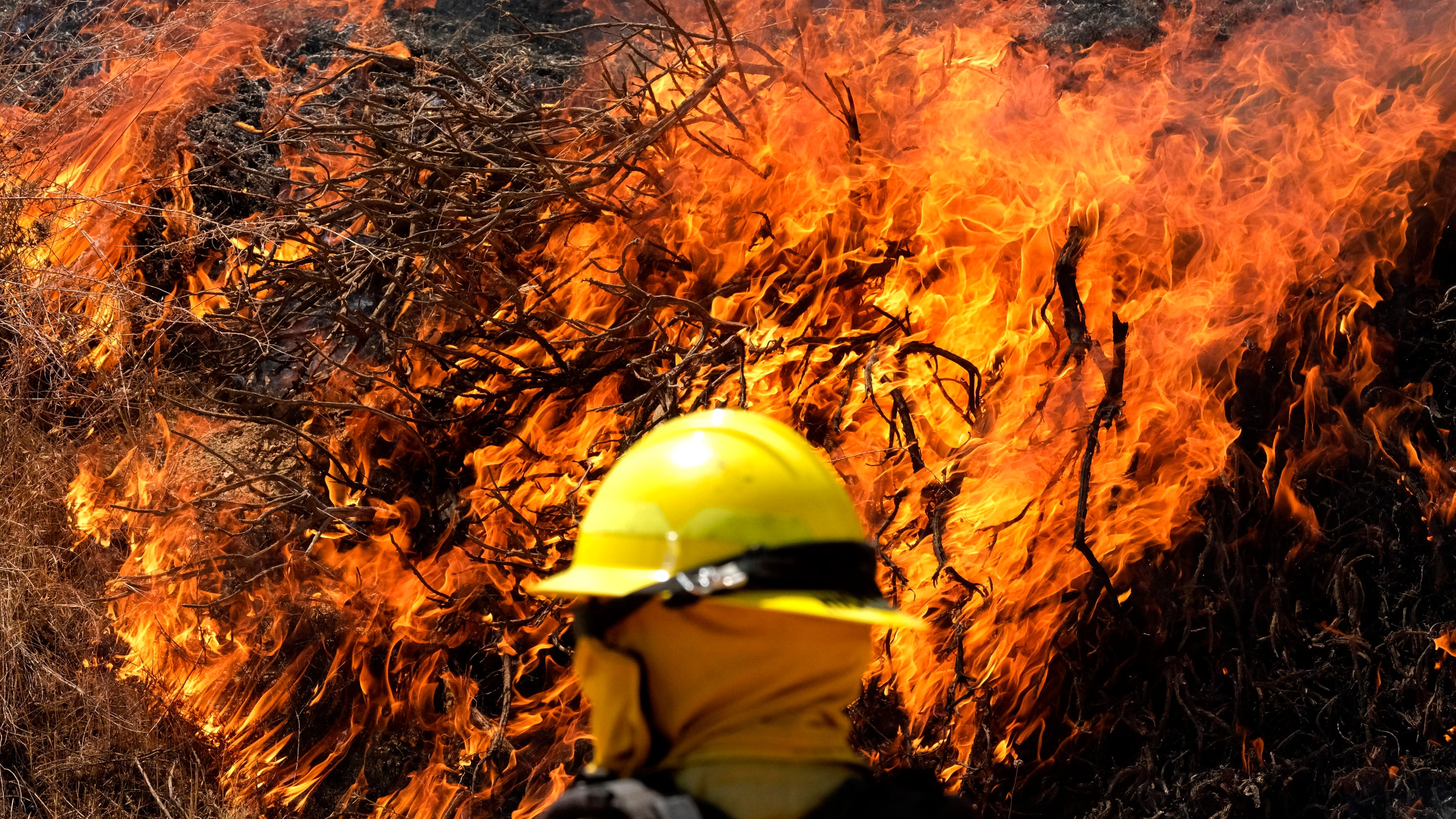 A firefighter watches the Apple Fire in Banning, Calif., Sunday, Aug. 2, 2020. (AP Photo/Ringo H.W. Chiu)
