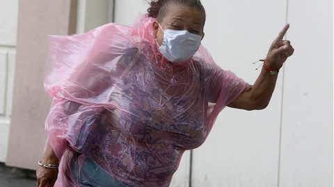 A woman shuts her eyes as she struggles to make her way into the Hard Rock Hotel & Casino during heavy winds, Tuesday, Aug. 4, 2020, in Atlantic City, NJ. Tropical Storm Isaias spawned tornadoes and dumped rain during an inland march up the U.S. East Coast, including New Jersey, on Tuesday after making landfall as a hurricane along the North Carolina coast. (AP Photo/Jacqueline Larma)