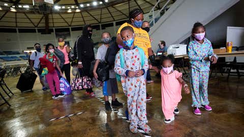 Victoria Nelson with her children Autum Nelson, 2, Shawn Nelson, 7, and Asia Nelson, 6, line up to board a bus to evacuate Lake Charles, La., Wednesday, Aug. 26, 2020, ahead of Hurricane Laura. (AP Photo/Gerald Herbert)