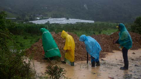 People walk around a road blocked by a landslide in Purulha, northern Guatemala Friday, Nov. 6, 2020. As the remnants of Hurricane Eta moved back over Caribbean waters, governments in Central America worked to tally the displaced and dead, and recover bodies from landslides and flooding that claimed dozens of lives from Guatemala to Panama. (AP Photo/Moises Castillo)