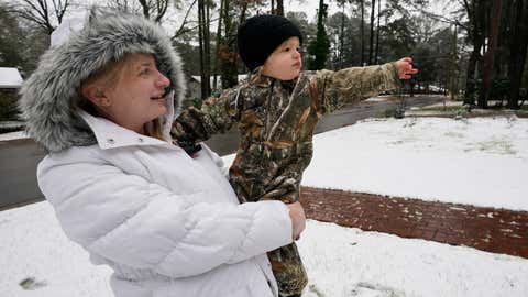 Luke West, 21 months, point out the snow covered yard to his mother, Anna Laura West, in Jackson, Miss., Monday morning, Jan. 11, 2021. A winter storm coated parts of Texas, Louisiana and Mississippi with snow on Sunday and into Monday morning. (AP Photo/Rogelio V. Solis)