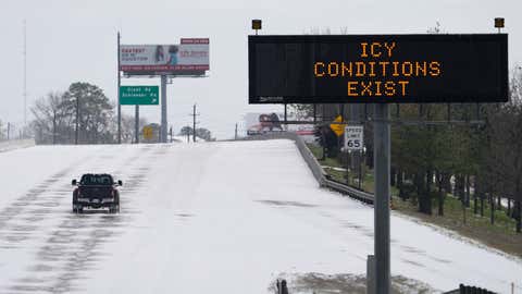 A truck drives past a highway sign Monday, Feb. 15, 2021, in Houston. A frigid blast of winter weather across the U.S. plunged Texas into an unusually icy emergency Monday that knocked out power to more than 2 million people and shut down grocery stores and dangerously snowy roads. (AP Photo/David J. Phillip)
