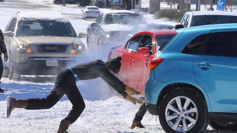 People push a car free after spinning out in the snow Monday, Feb. 15, 2021 in Waco, Texas. A winter storm that brought snow, ice and plunging temperatures across the southern Plains and caused a power emergency in Texas stretched its frigid fingers down to the Gulf Coast. (Jerry Larson/Waco Tribune-Herald via AP)