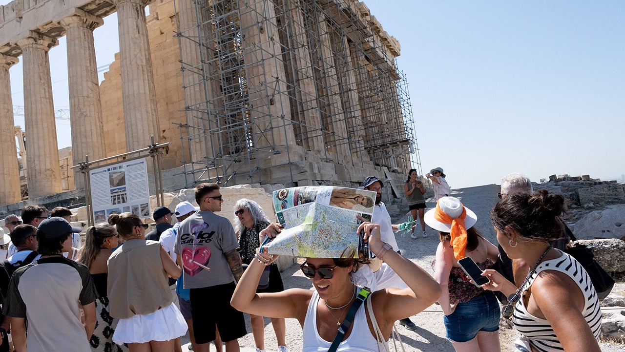 Thousands of tourists wear hats and carry umbrellas for protection as they visit the Acropolis during the worst heatwave of the season in Athens, Greece, on July 23, 2025.
