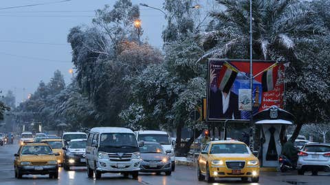 BAGHDAD,IRAQ - FEBRUARY 11:Vehicles,most with their lights on,go on a road during snowfall in Baghdad,Iraq on February 11,2020. (Photo by Murtadha Al-Sudani/Anadolu Agency via Getty Images)