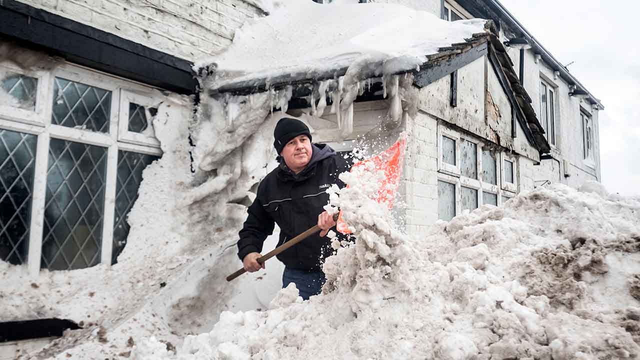 Public House landlord ,Angus Wharton, clears snow outside the Ye Olde Black Ladd pub in Shaw, Greater Manchester England, Friday March 2, 2018. The big freeze caused travel chaos throughout the country with hundreds of flights cancelled at Heathrow Airport, Europe's largest air hub. Trains broke down, stranding some passengers in frosty conditions for hours. (Danny Lawson/PA via AP) 
