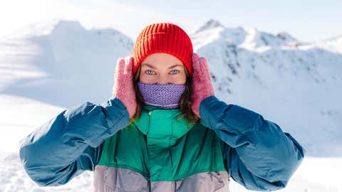 Woman in snowy mountains with colorful winter clothes