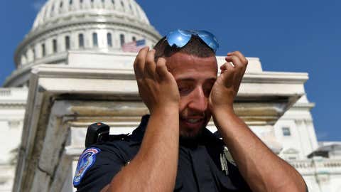 A police officer wipes sweat from his eyes as he stands his post on the west side of Capitol Hill in Washington, Saturday, July 20, 2019. (AP Photo/Susan Walsh)