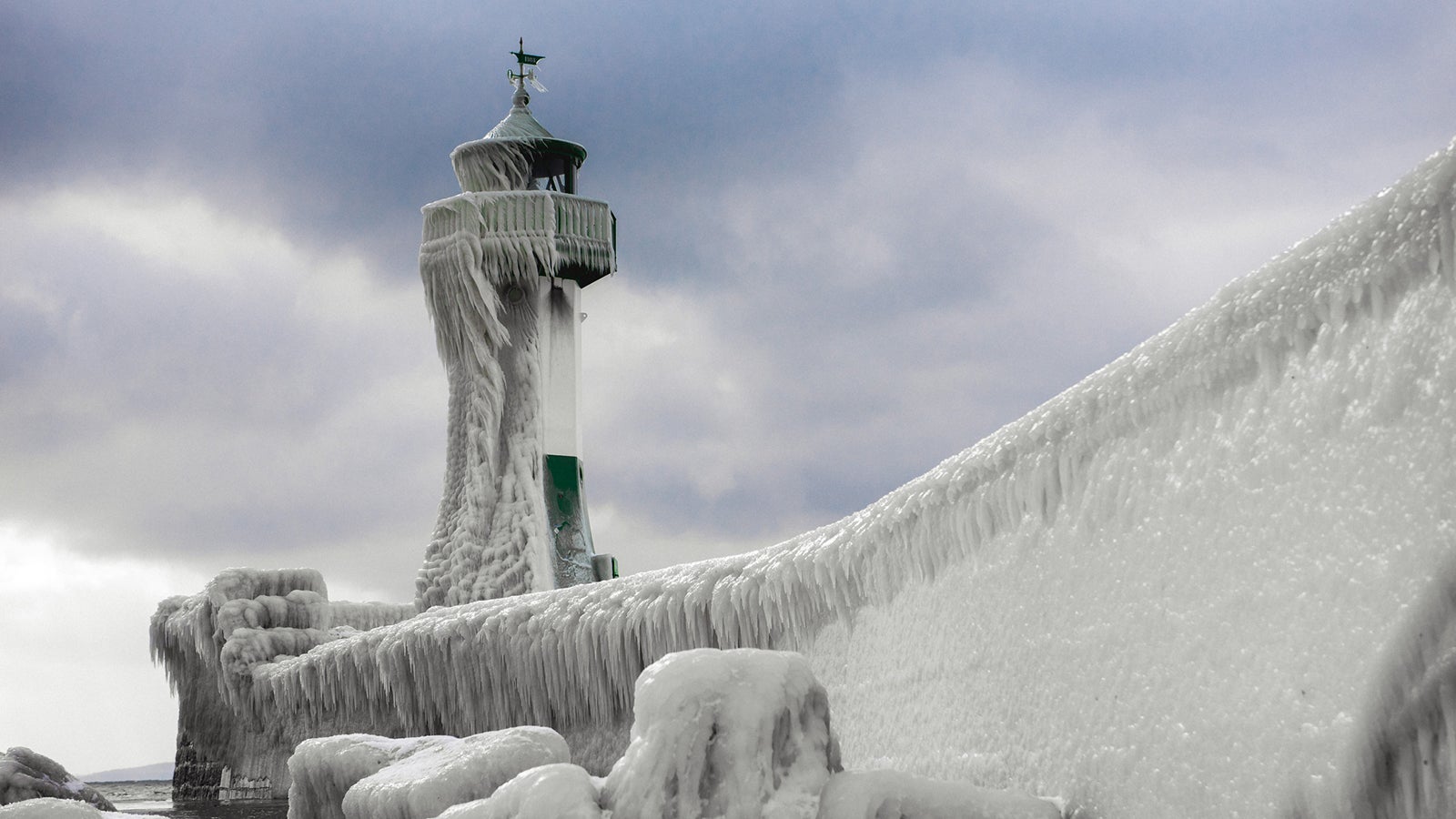 Lighthouse on the baltic sea in winter with frozen water and icicles on it