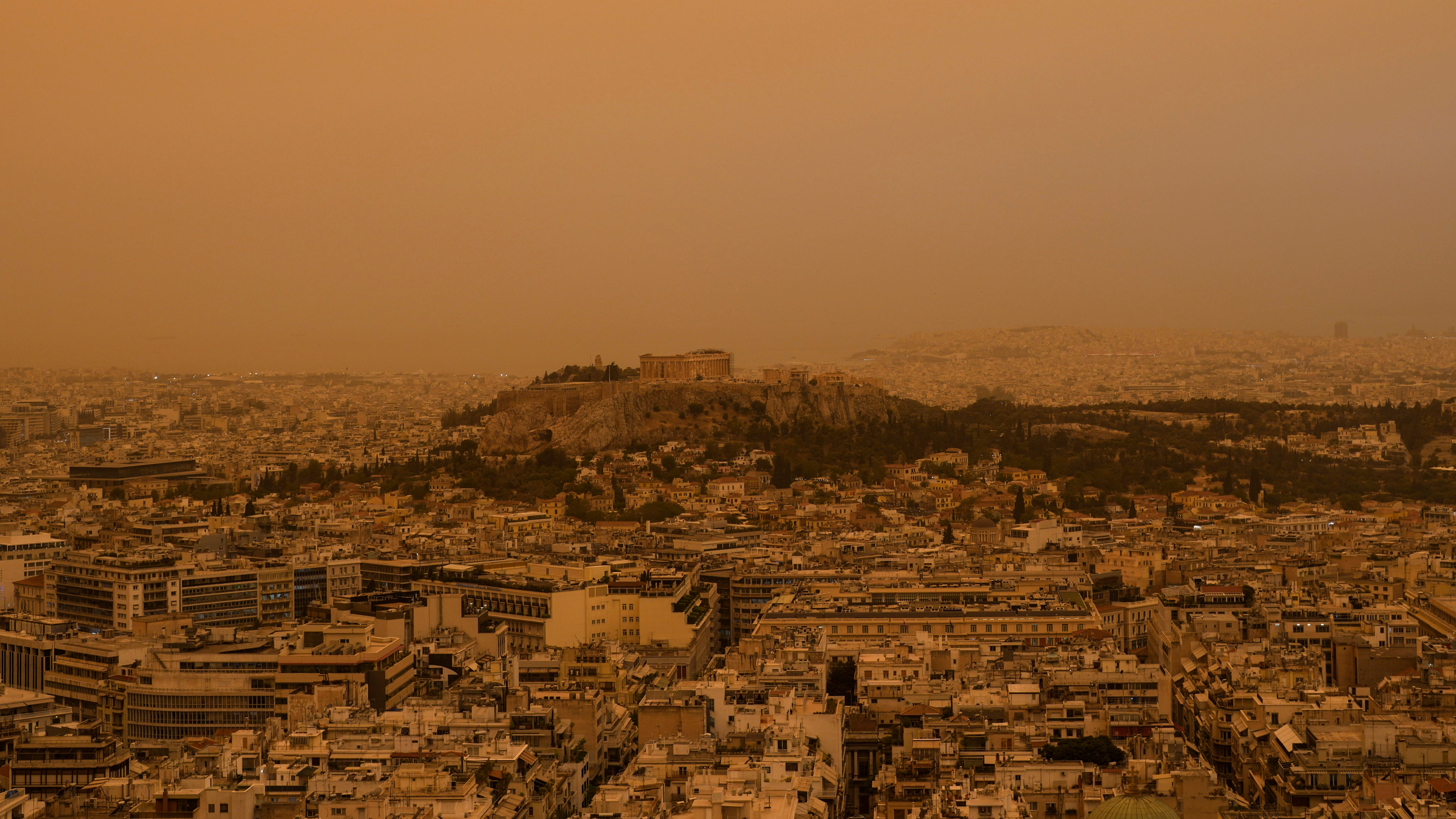 23.04.2024, Griechenland, Athen: Der antike Akropolis-H&uuml;gel und die Stadt Athen vom Lycabettus-H&uuml;gel aus gesehen. Die Akropolis und andere Wahrzeichen Athens nahmen am Dienstag einen mars&auml;hnlichen Farbton an, als erstickende Staubwolken, die von Nordafrika &uuml;ber das Mittelmeer geweht wurden, die griechische Hauptstadt einh&uuml;llten. (Petros Giannakouris/AP/dpa)

