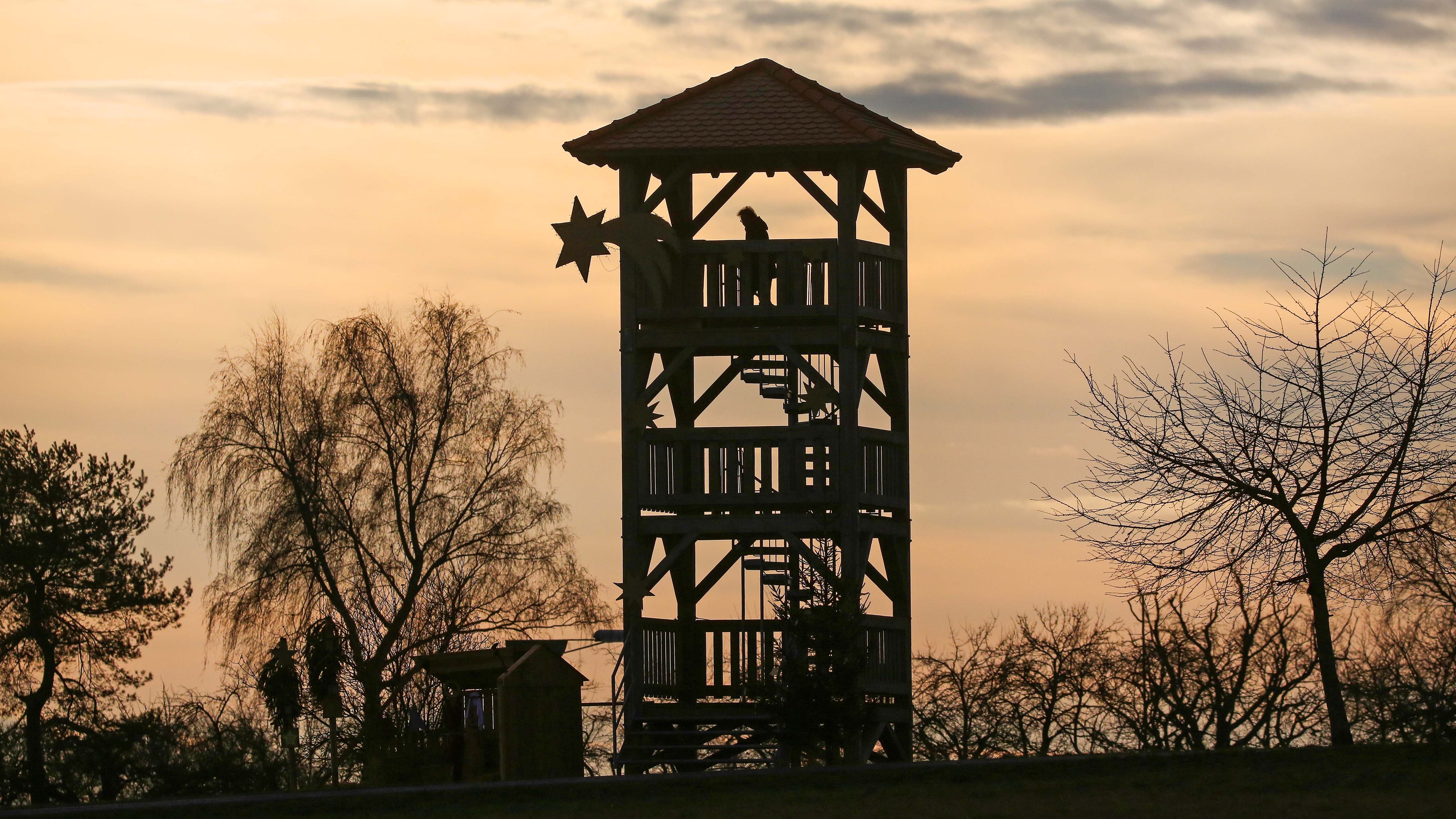 26.12.2022, Baden-W&uuml;rttemberg, Bad Buchau: Eine Frau steht auf einem Aussichtsturm an dem ein Weihnachsstern befestigt ist. Foto: Thomas Warnack/dpa +++ dpa-Bildfunk +++